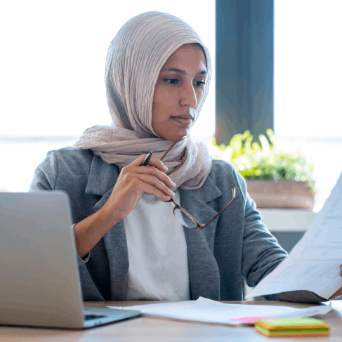 A translator compares Arabic birth records to English pages, providing USCIS recognized Arabic Translation Services in Iowa.